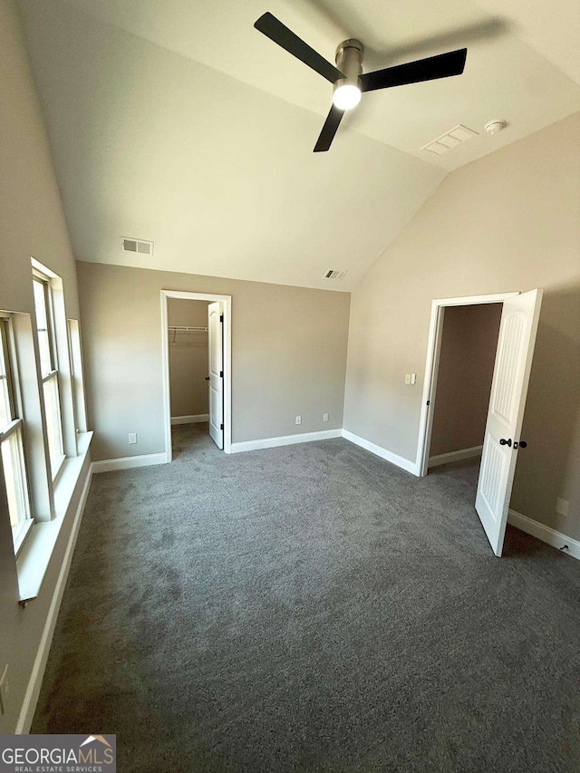 unfurnished bedroom with vaulted ceiling, dark colored carpet, and baseboards