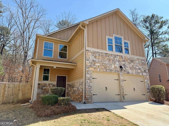 view of front of house with an attached garage, fence, stone siding, concrete driveway, and board and batten siding