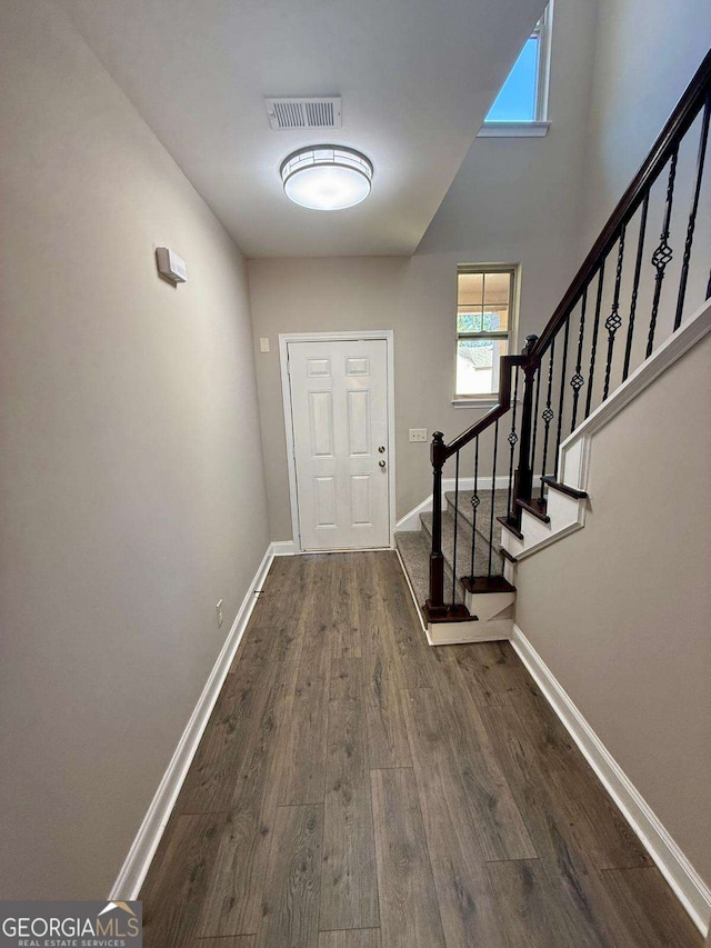 entryway with dark wood-style floors, visible vents, stairway, and baseboards