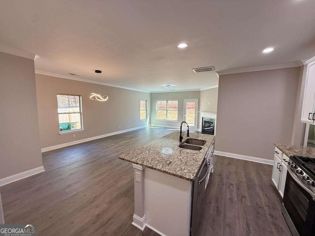 kitchen featuring a fireplace, a sink, white cabinetry, appliances with stainless steel finishes, and dark wood-style floors