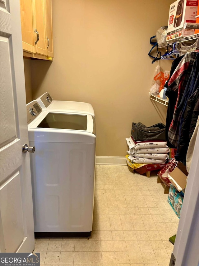 laundry area featuring washer and clothes dryer, cabinet space, and baseboards