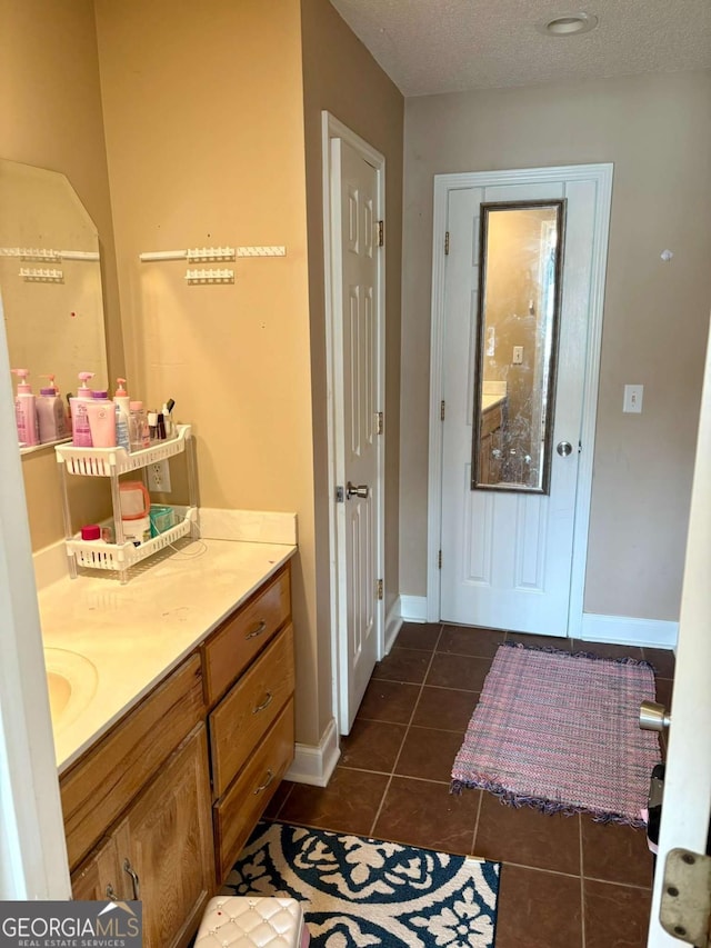 bathroom featuring tile patterned flooring, baseboards, a textured ceiling, and vanity