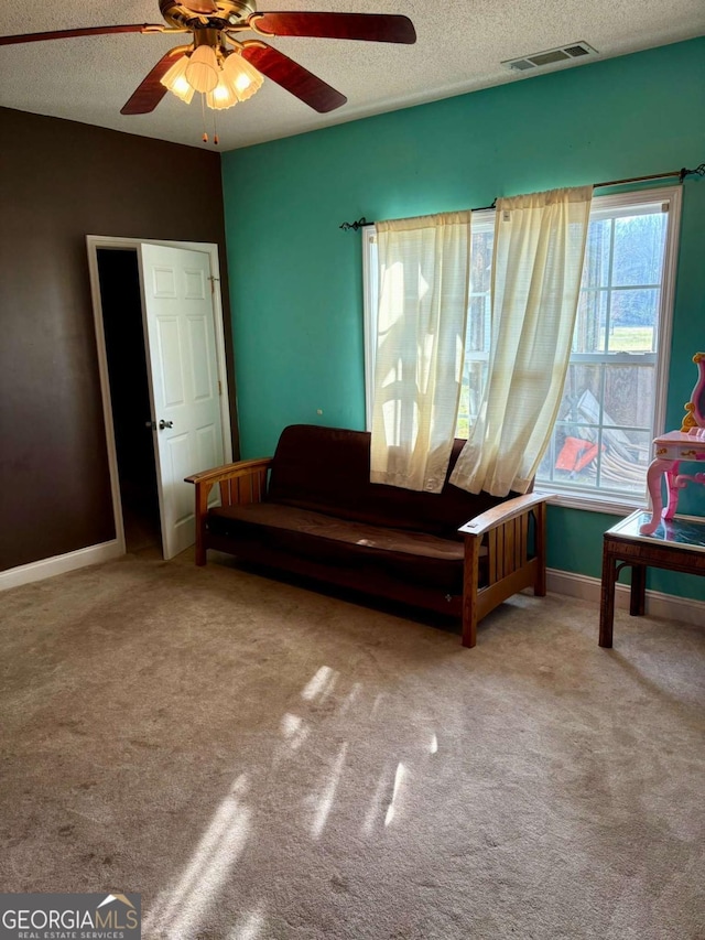 sitting room with a textured ceiling, carpet floors, and visible vents