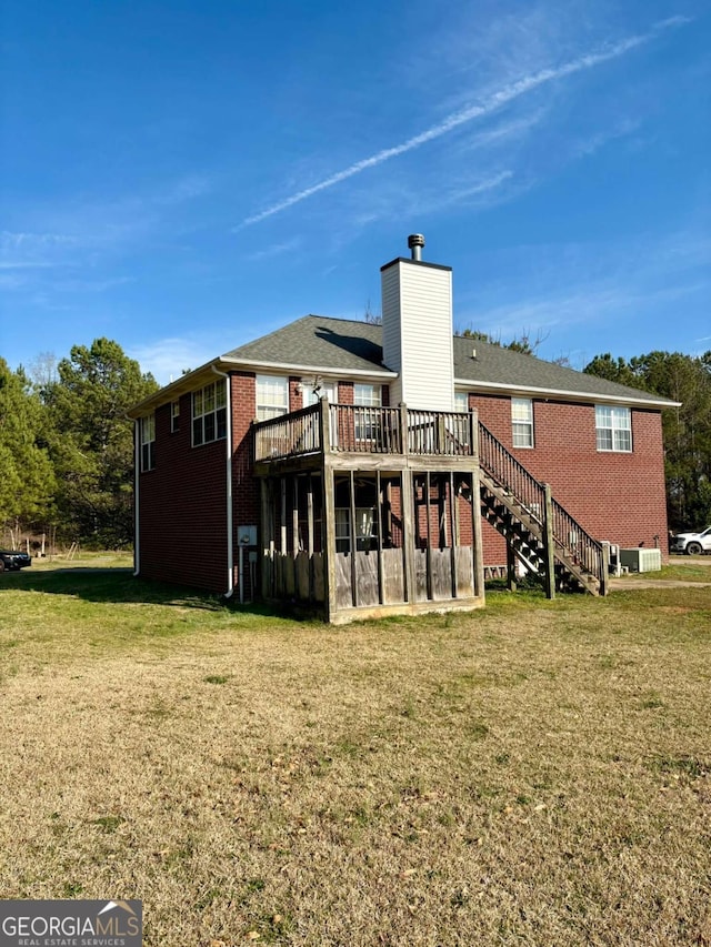 rear view of property with brick siding, a lawn, a wooden deck, and stairs