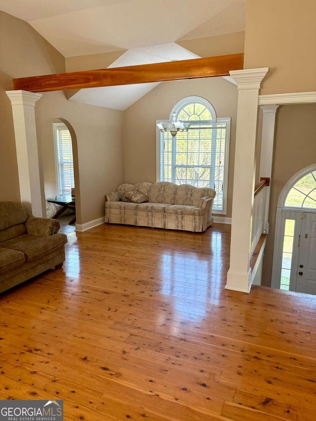 unfurnished living room featuring arched walkways, vaulted ceiling, and hardwood / wood-style floors