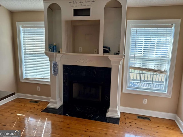 room details with a fireplace with flush hearth, visible vents, baseboards, and wood finished floors