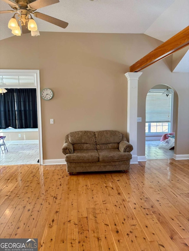 living room with lofted ceiling, ceiling fan, arched walkways, and hardwood / wood-style flooring