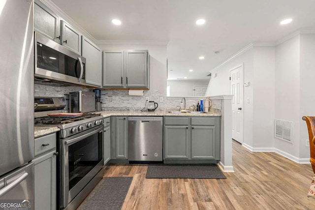 kitchen featuring light wood-style flooring, gray cabinetry, a sink, visible vents, and appliances with stainless steel finishes