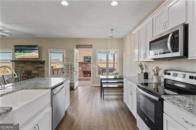 kitchen featuring dark wood-style floors, a fireplace, appliances with stainless steel finishes, white cabinetry, and a sink