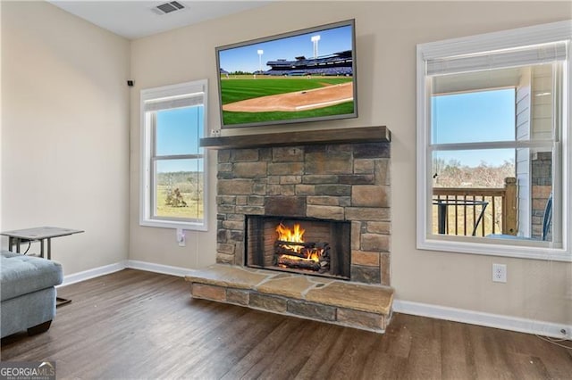 living area with visible vents, a fireplace, wood finished floors, and a wealth of natural light