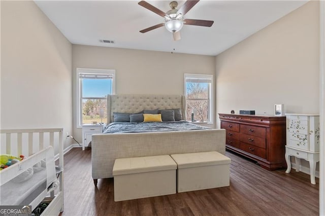 bedroom with dark wood-type flooring, multiple windows, and visible vents