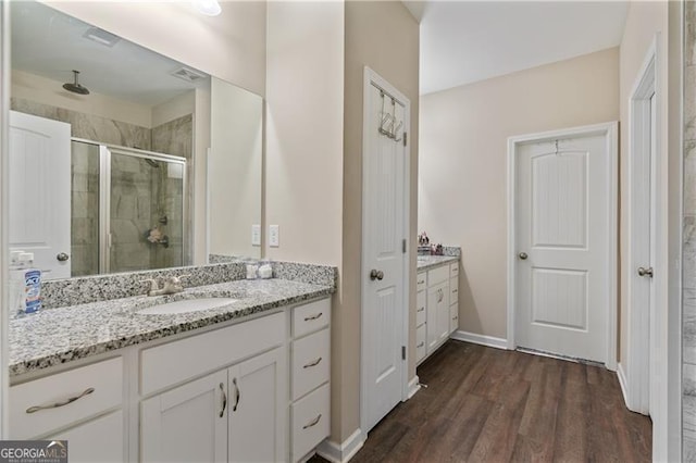 full bath with a stall shower, baseboards, wood finished floors, and vanity