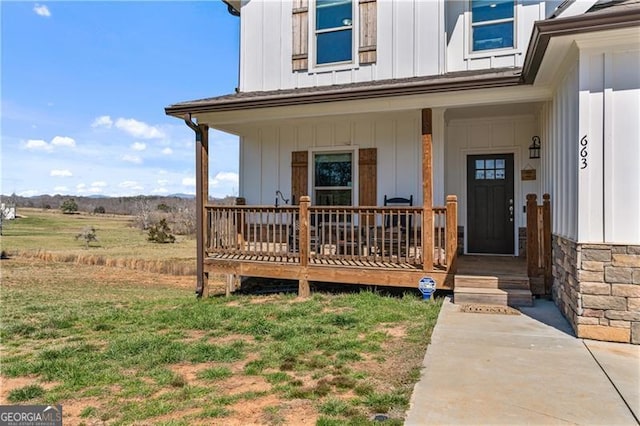 view of exterior entry with a yard, a porch, and board and batten siding