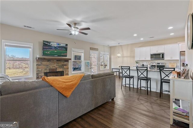 living area featuring a healthy amount of sunlight, dark wood-style floors, a fireplace, and recessed lighting