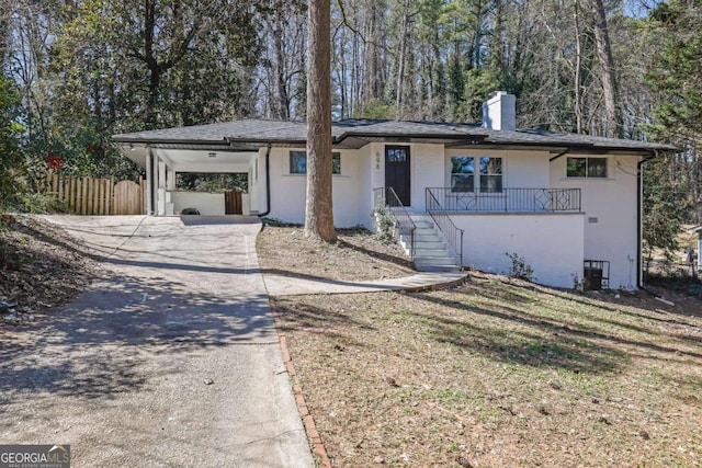 view of front of house featuring a chimney, concrete driveway, a front yard, fence, and an attached carport