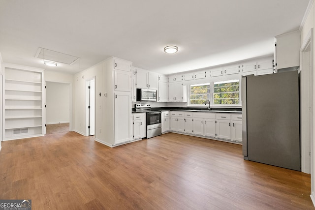 kitchen featuring visible vents, dark countertops, appliances with stainless steel finishes, light wood-type flooring, and white cabinetry