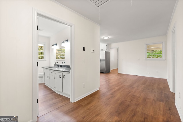 corridor with attic access, a sink, baseboards, and wood finished floors