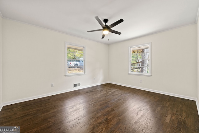 spare room featuring a healthy amount of sunlight, visible vents, and dark wood-style flooring