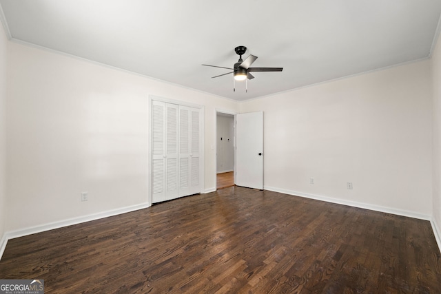 unfurnished bedroom with a closet, dark wood-type flooring, ornamental molding, a ceiling fan, and baseboards