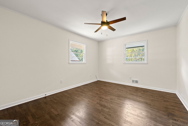 spare room with dark wood-style floors, plenty of natural light, visible vents, and baseboards