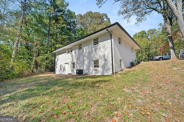 exterior space featuring central AC unit, a lawn, and brick siding