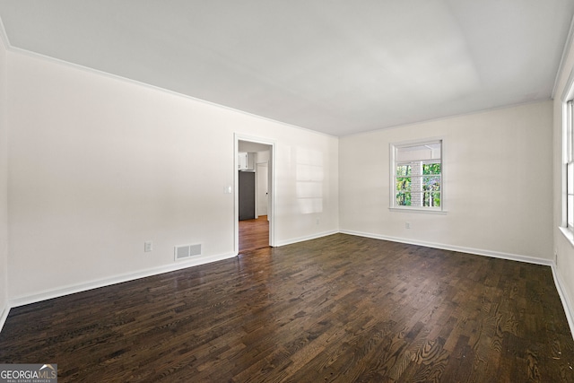 unfurnished room featuring baseboards, visible vents, and dark wood finished floors