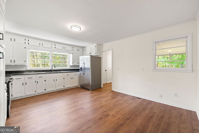 kitchen with a sink, dark countertops, stainless steel fridge, and white cabinetry