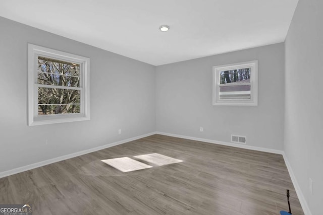 spare room with a wealth of natural light, visible vents, and baseboards