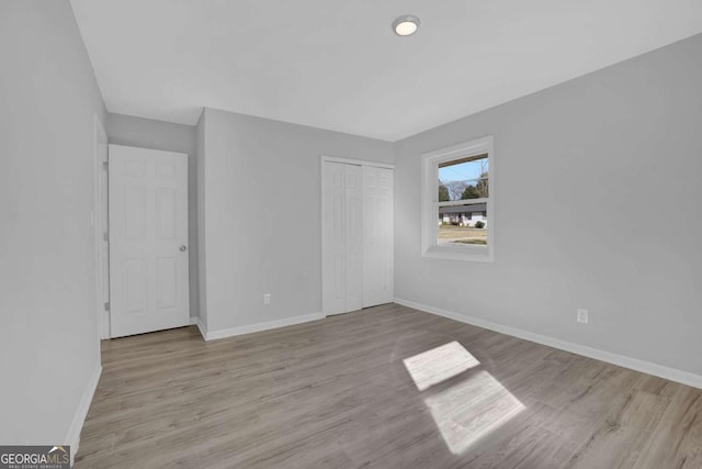 unfurnished bedroom featuring a closet, baseboards, and wood finished floors