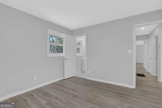 spare room with visible vents, baseboards, and wood finished floors