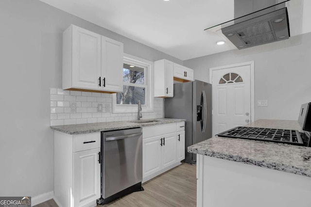 kitchen with light wood finished floors, decorative backsplash, light stone countertops, stainless steel appliances, and a sink