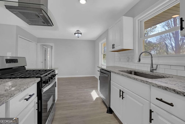 kitchen with a sink, white cabinetry, appliances with stainless steel finishes, light wood-type flooring, and tasteful backsplash