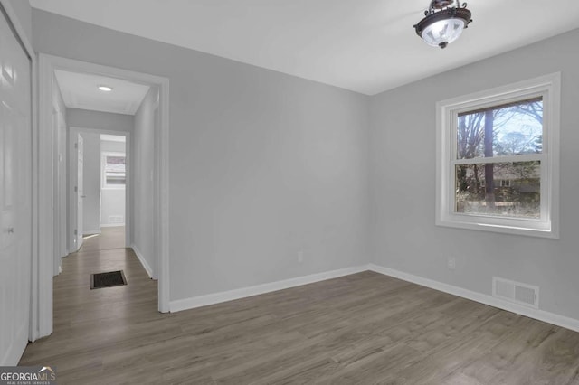 unfurnished dining area featuring baseboards, visible vents, and wood finished floors