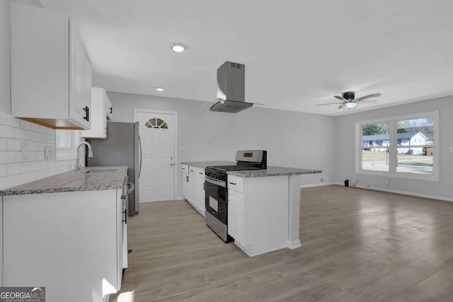 kitchen featuring ventilation hood, light wood-style floors, white cabinetry, backsplash, and gas stove