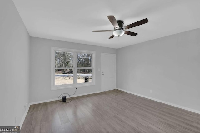 empty room with ceiling fan, baseboards, and wood finished floors