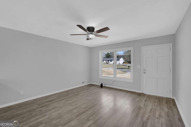 interior space featuring ceiling fan, wood finished floors, visible vents, and baseboards