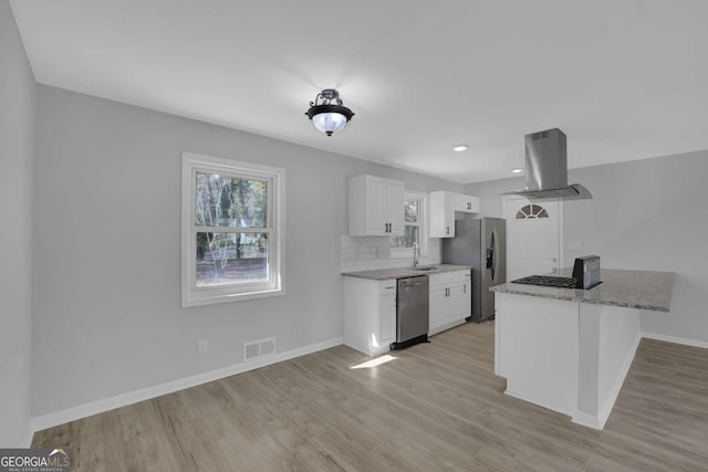 kitchen with island exhaust hood, stainless steel appliances, a healthy amount of sunlight, white cabinetry, and a sink