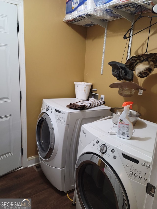 clothes washing area featuring laundry area, washing machine and dryer, and dark wood-type flooring