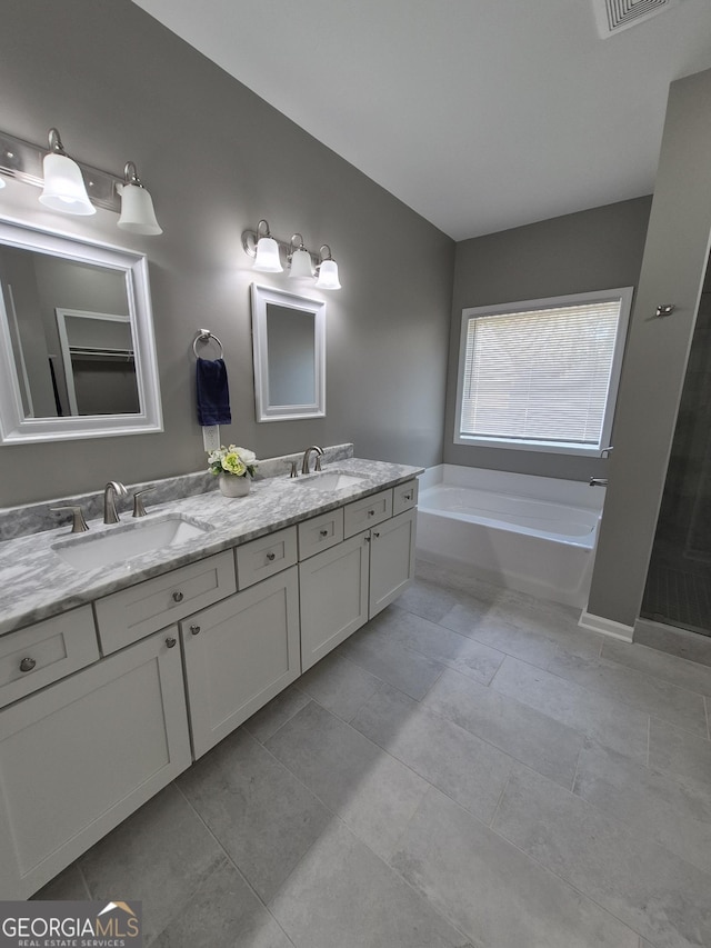 bathroom with double vanity, a sink, and a bath