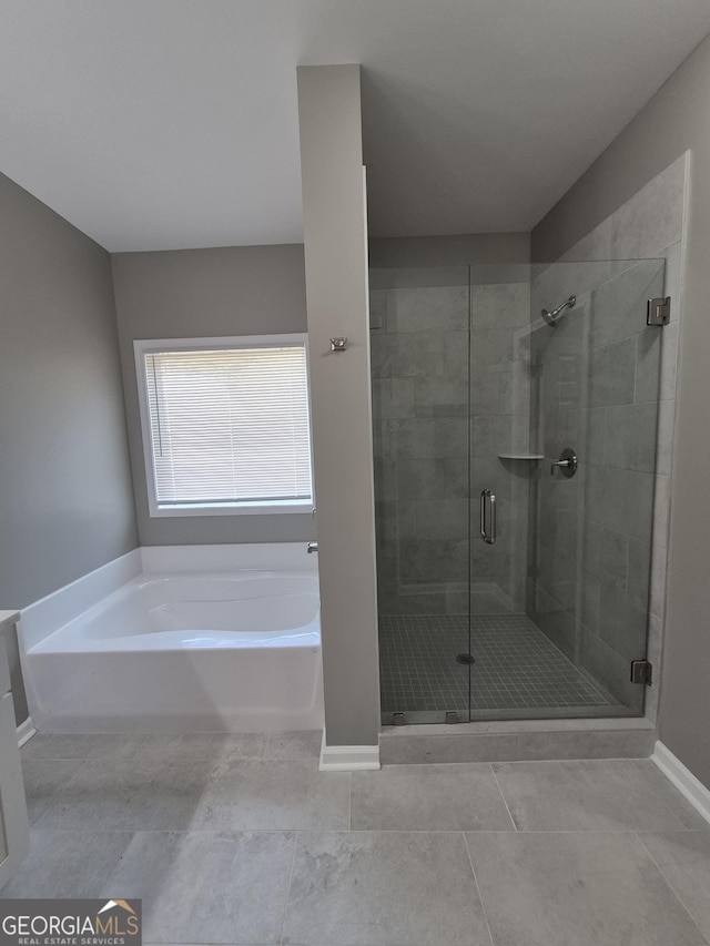 bathroom with a garden tub, baseboards, and a stall shower