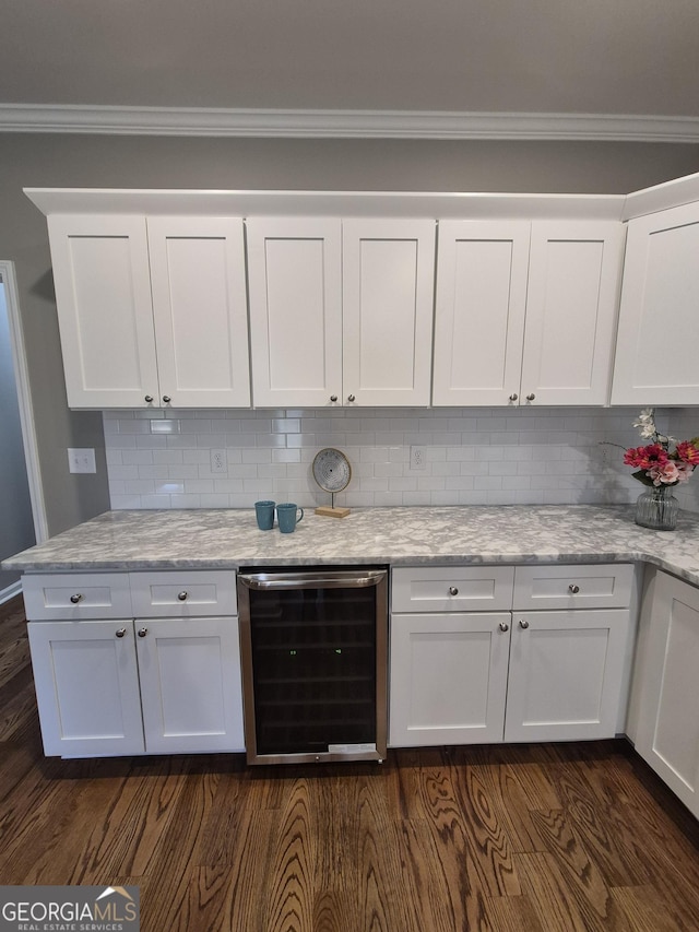 kitchen with beverage cooler, decorative backsplash, ornamental molding, dark wood-type flooring, and white cabinetry