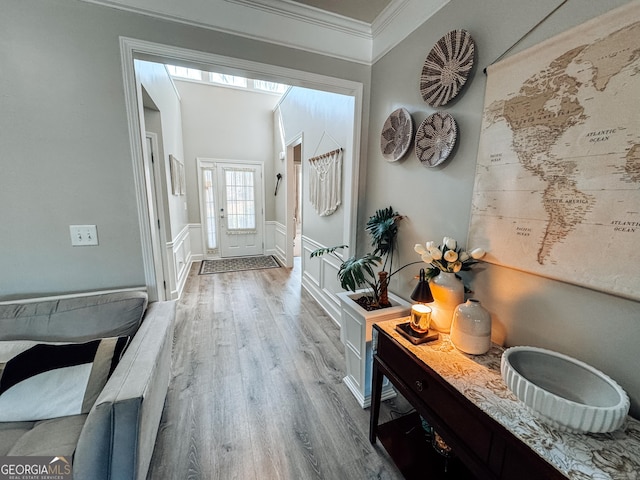 hallway with wainscoting, a decorative wall, crown molding, and wood finished floors