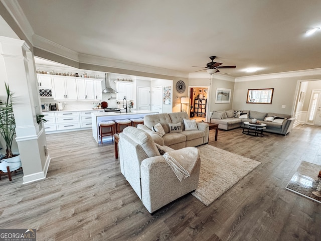 living room featuring light wood finished floors, ceiling fan, and crown molding