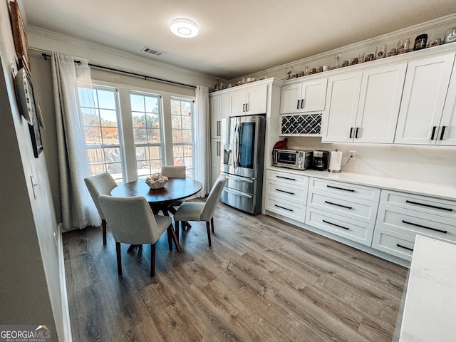 kitchen featuring light wood finished floors, white cabinetry, visible vents, and stainless steel fridge with ice dispenser