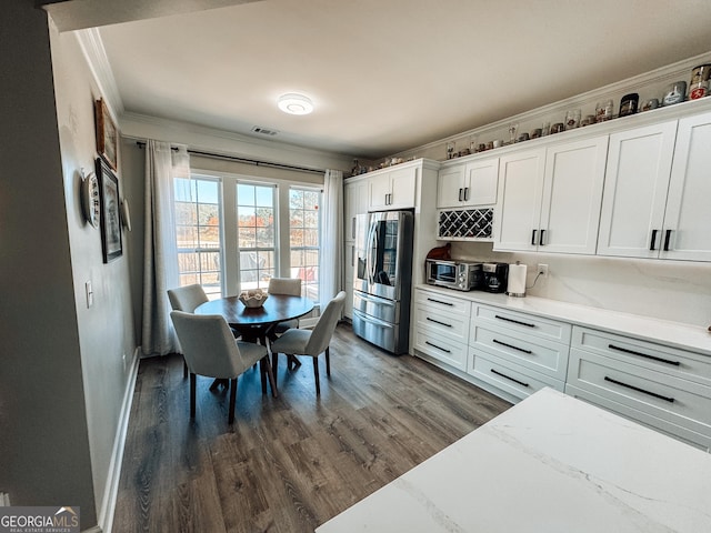 kitchen with visible vents, white cabinets, dark wood finished floors, ornamental molding, and stainless steel refrigerator with ice dispenser