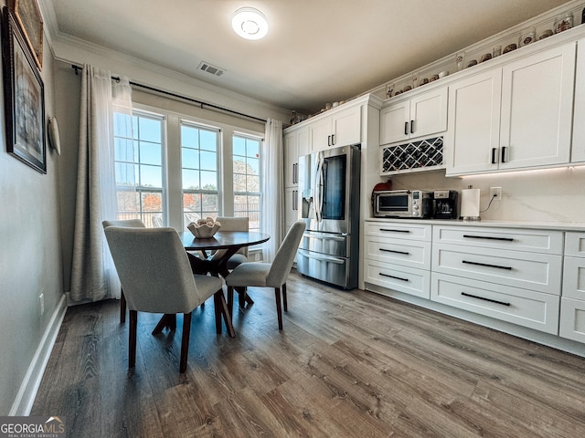 dining space with dark wood-style floors, ornamental molding, visible vents, and baseboards