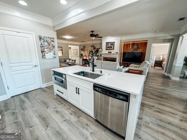 kitchen with appliances with stainless steel finishes, light wood-type flooring, open floor plan, and a sink
