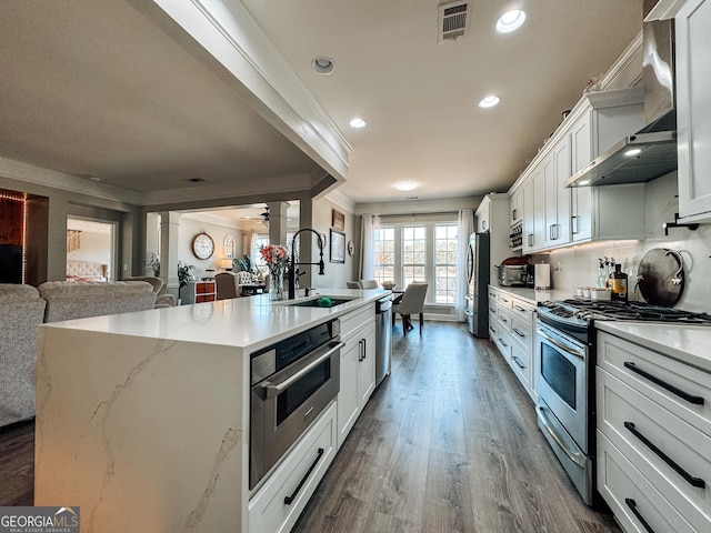 kitchen featuring stainless steel appliances, a sink, visible vents, ornamental molding, and ornate columns