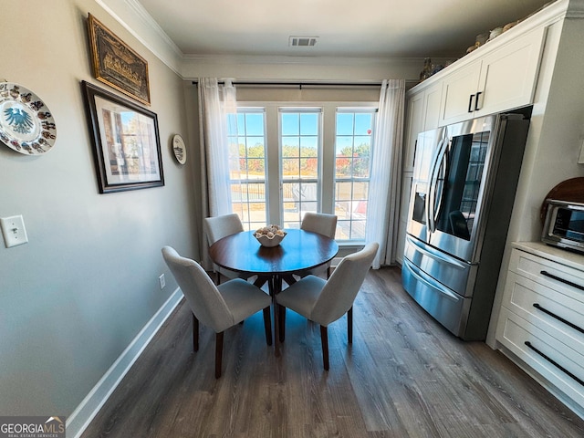 dining area featuring a toaster, dark wood-type flooring, visible vents, baseboards, and crown molding