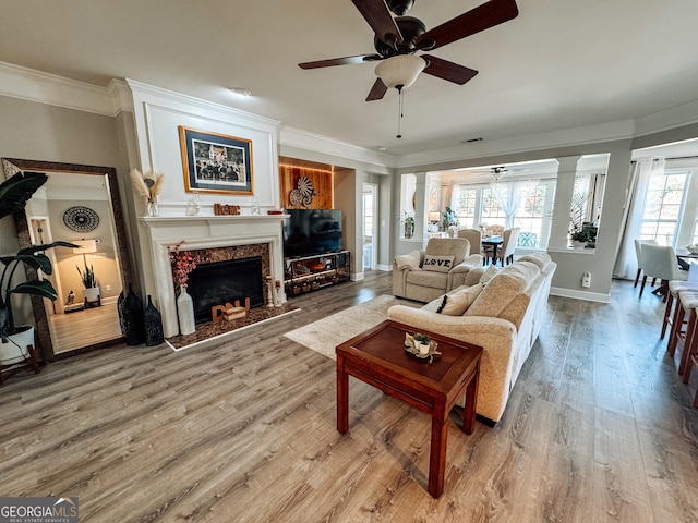 living room with crown molding, decorative columns, ceiling fan, and wood finished floors